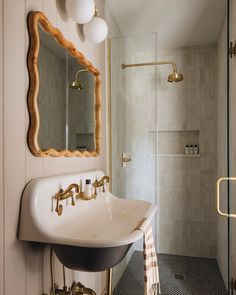 a white sink sitting under a mirror in a bathroom next to a walk in shower