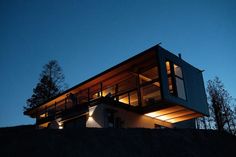 two people standing on the top of a hill at night with lights shining from their windows