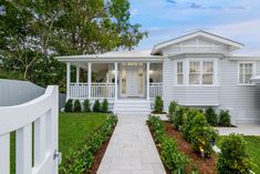 a white house with a front yard and walkway leading to the front door is surrounded by greenery