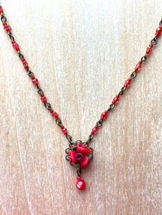 Colleen Toland Valentines Red Rose Pendant Necklace. Elegant and simple, this tiny red rose necklace is a handmade polymer clay flower that is beaded together with seed beads all the way around the edge and a single drop bead in the center. The necklace is hand-beaded with red glass seed beads and eye-pins.  The closure is a hook with a 4 inch extender.  The necklace measures 15 inches long not including the extender. This is a quality piece of jewelry that will last a life time. Created by designer Colleen Toland who has been creating her unique style of vintage jewelry for more than 30 years. All of our pieces come with an engraved tag with Colleen's name so as you know you are receiving authentic Colleen Toland jewelry. Necklace measures 20 inches with a 4 inch extender so as you can ch Handmade Rose Necklace For Valentine's Day, Rose Necklaces For Valentine's Day, Red Flower-shaped Beaded Necklace For Gift, Red Flower-shaped Necklace For Gifts, Rose Pendant Necklace, Red Flower-shaped Necklace With Rose Design, Necklace Elegant, Rose Pendant, Clay Flower