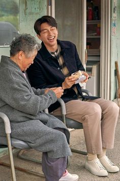 an elderly man sitting on a chair next to another person