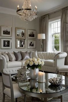 a living room filled with furniture and a chandelier above a glass top table