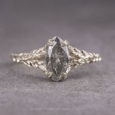 a white gold engagement ring with a pear shaped diamond in the center and leaves around it