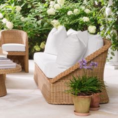 wicker furniture with white pillows and flowers in the background