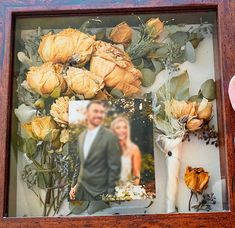 a wooden frame with an image of a bride and groom surrounded by flowers, greenery and croissants