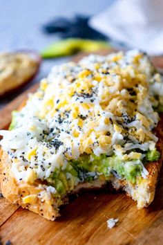 a piece of bread with cheese and broccoli on it sitting on a cutting board