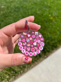 a hand holding a keychain with pink flowers and skulls on it that says brindle