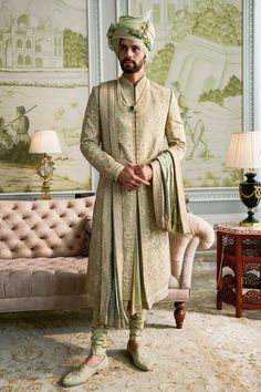 a man standing in front of a couch wearing a turban and dress clothes