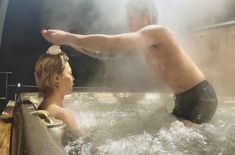 a man and woman in a hot tub with steam coming out of the back wall