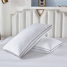 two pillows on top of a white bed