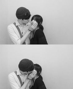 two people are kissing each other in front of a wall and one person is covering their face with his hands