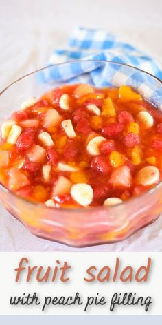 fruit salad with peach pie filling in a glass bowl on a blue and white checkered cloth