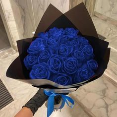 a bouquet of blue roses wrapped in black paper