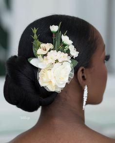 the back of a woman's head with flowers in her hair and earrings on