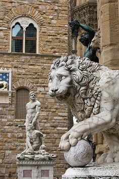 a statue of a lion is in front of a building with statues on either side