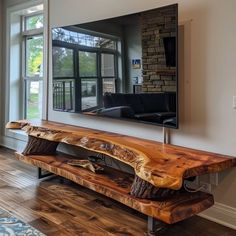 a wooden bench sitting in front of a large tv mounted on a wall next to a window