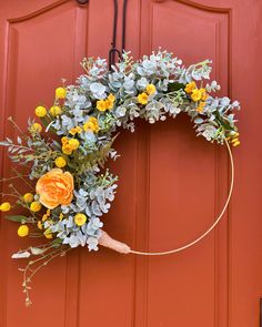 a wreath with flowers hanging on a red door