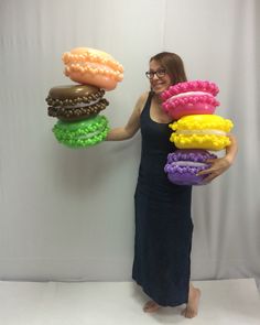 a woman in a black dress is holding some doughnuts on her arms and smiling