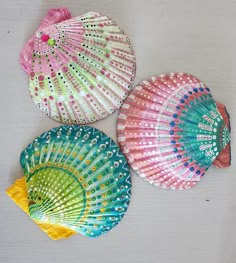 three colorful fan shaped objects on a white surface