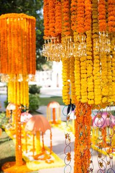 many orange and yellow flowers are hanging from the ceiling in front of an outdoor venue