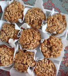 muffins with crumbled toppings sitting in white paper wrappers on a floral table cloth