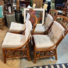 four wicker chairs with beige cushions in a store