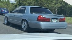 a silver car driving down a street next to another car on the side of the road