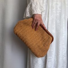 a woman is holding a brown woven purse