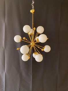 a chandelier hanging from the ceiling with white glass balls and gold trimmings