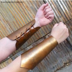 a person wearing gold leather bracelets and holding onto a metal object with one hand