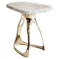 a white marble topped stool with gold metal legs and an intricate design on the top