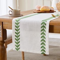 a table topped with a white and green table runner next to a wooden table top