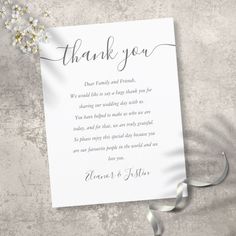 a wedding thank card with flowers and ribbon on the side, sitting on a table