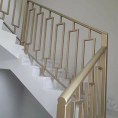 a white staircase with gold railing and handrail