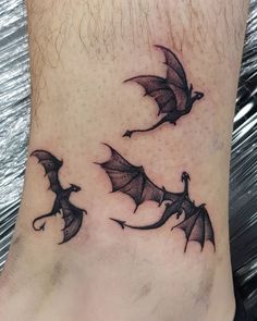 a tattoo on the foot of a person with two bats flying through the night sky