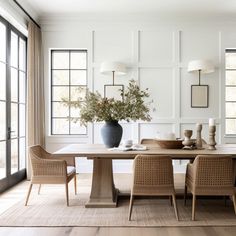 a dining room table with chairs and a vase on the table in front of it