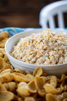 a white bowl filled with food next to chips