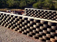 a large pile of tires sitting on top of a gravel road next to a forest