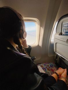 a woman sitting on an airplane seat looking out the window at the ocean and sky