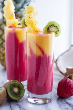 two glasses filled with fruit smoothie next to sliced kiwis