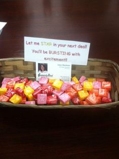 a basket filled with lots of candy sitting on top of a wooden table next to a sign