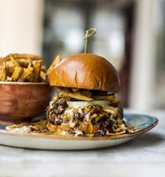 a cheeseburger on a plate next to a bowl of fries