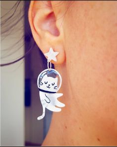 a close up of a person's ear wearing earrings with an image of a cat on it