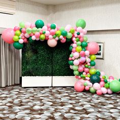 an arch made out of balloons on top of a carpeted floor in front of a window