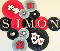 some casino themed paper plates on a white table with black and red decorations that spell out the word simon