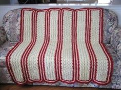 a red and white afghan sitting on top of a couch