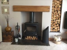 a wood burning stove sitting in a living room next to a pile of firewood