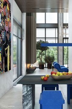 a modern dining room with blue chairs and art on the wall behind it, along with fruit