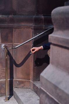 a man in a suit and tie walking up stairs with his hand on the railing