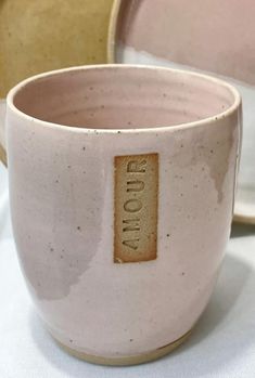 two ceramic cups sitting next to each other on a white tablecloth covered table cloth